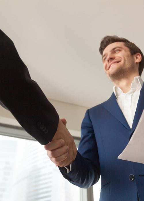 Satisfied businessman with business documents shaking hand to partner, making deal after reviewing terms of contract, offering profitable project to investor, happy of partnership, welcoming client